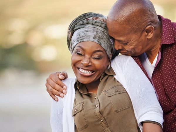 A happy couple smiling and embracing each other outdoors.